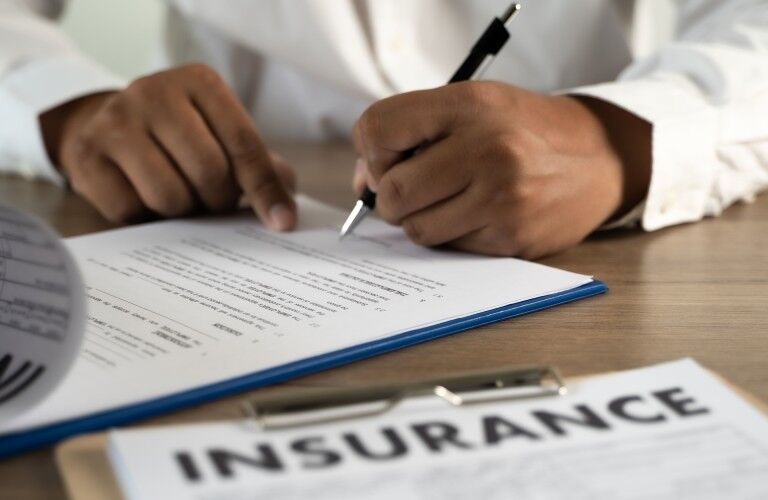 person signing papers in an office for insurance