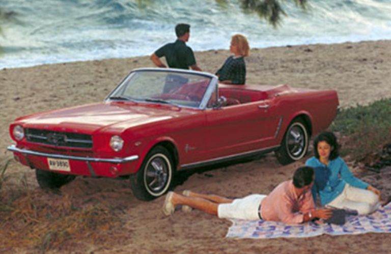 front quarter view of the 1964 Ford Mustang on a beach with two couples enjoying themselves