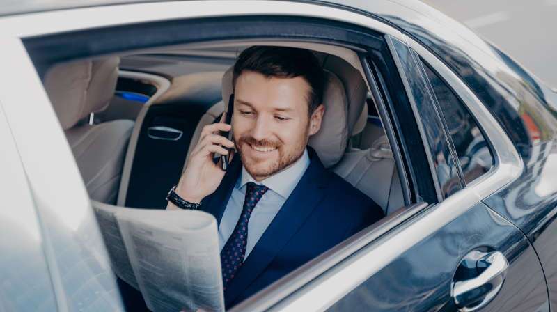 A man being chauffeured in a luxury car he financed