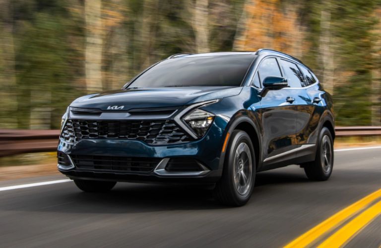 2023 Kia Sportage Hybrid Driving Down a Forest Road Three-Quarter View