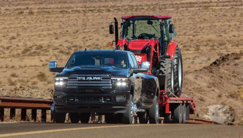 A front 3/4 external view of the 2026 Ram 3500 towing a large tractor