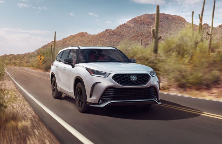 A 2023 Toyota Highlander speeding on a smooth countryside road