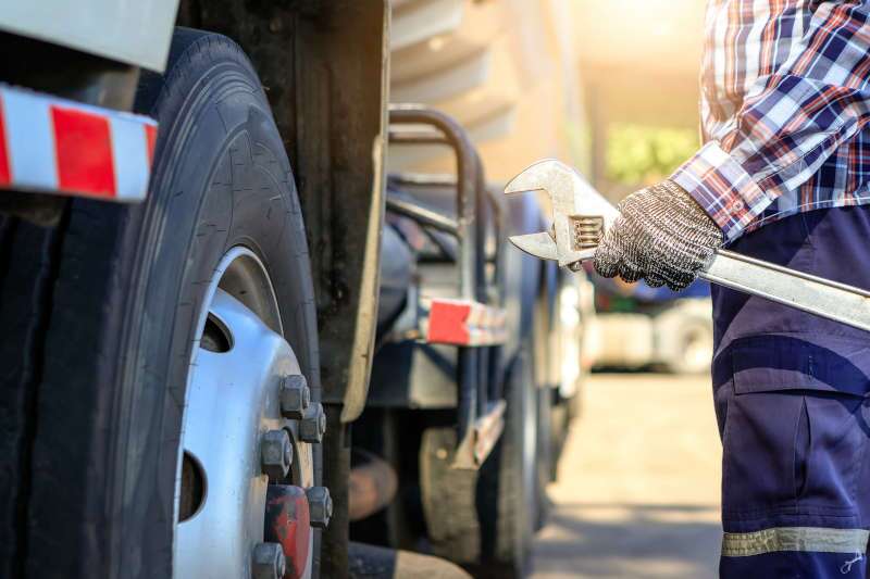 A man approaching a large heavy truck to perform preventative maintenance