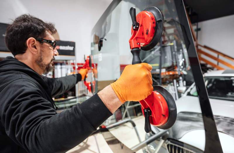 A man replacing a car's windshield.