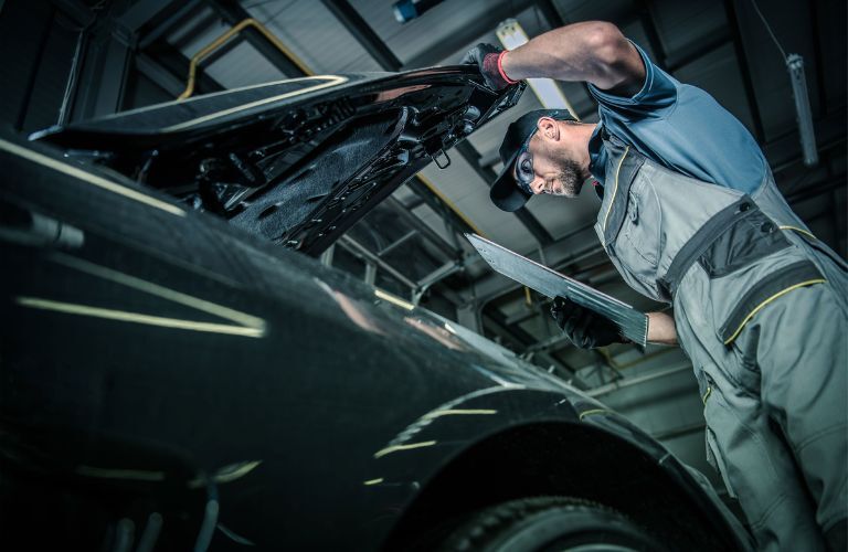 technician looking under the hood of a vehicle