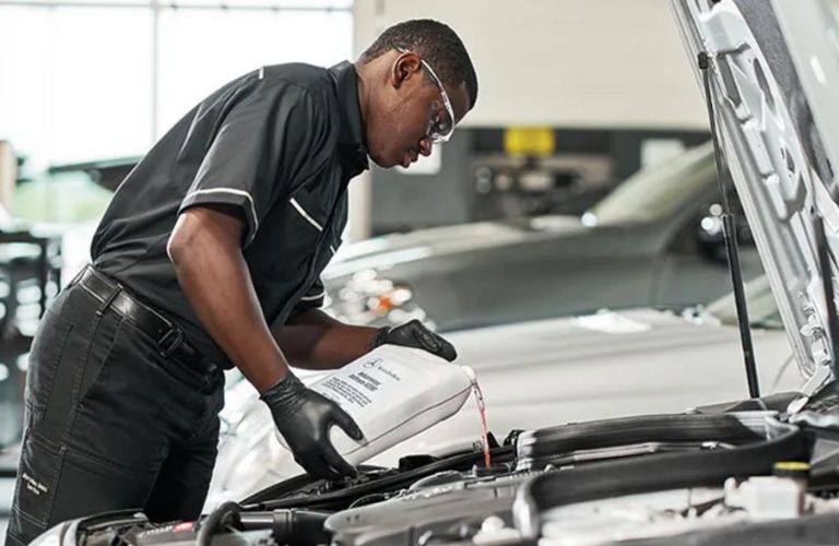 a technician working under the hood of a Mercedes-Benz