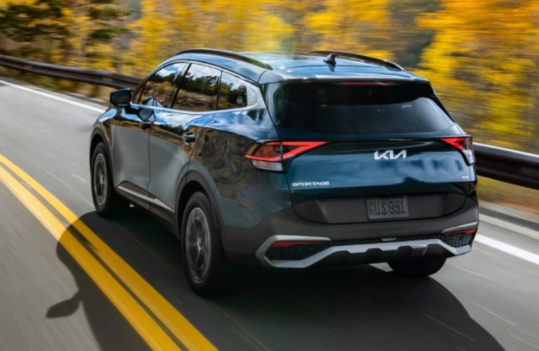 2023 Kia Sportage Hybrid Driving Fast Down a Road Rear Three-Quarter View