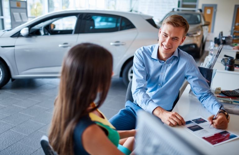 salesman selling car to woman inside car dealership
