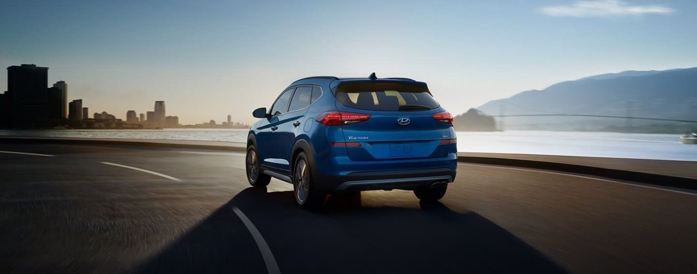 A blue 2020 Hyundai Tucson is shown driving past water.