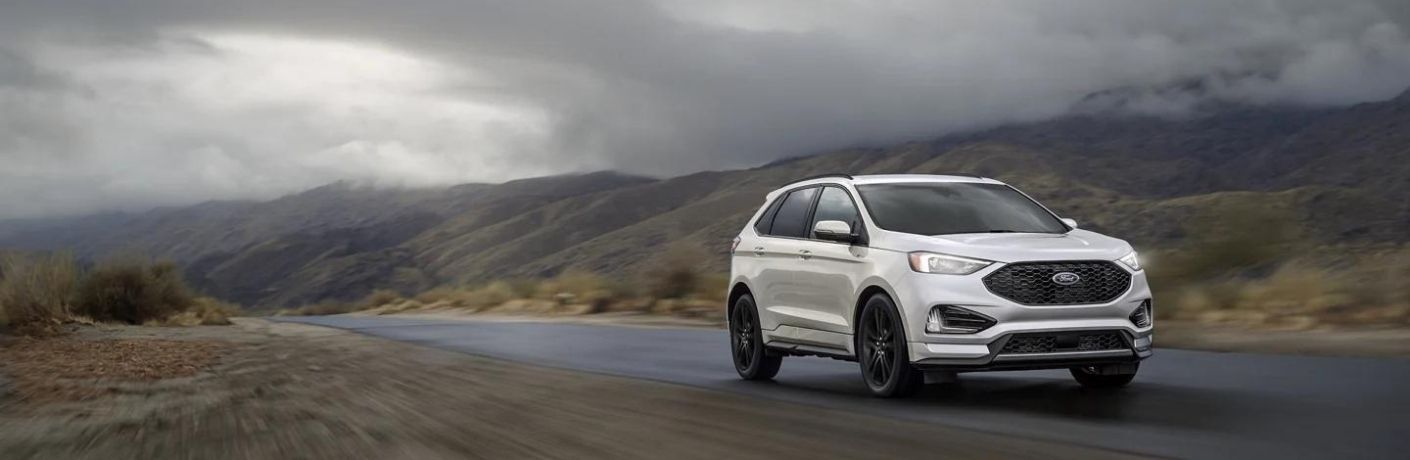 A white 2022 Ford Edge driving on the mountain road.