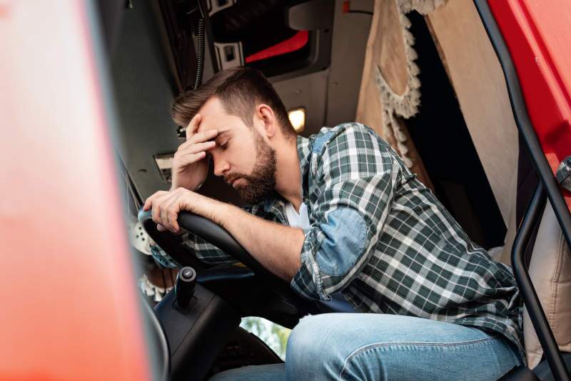 A fatigued truck driver in his truck.