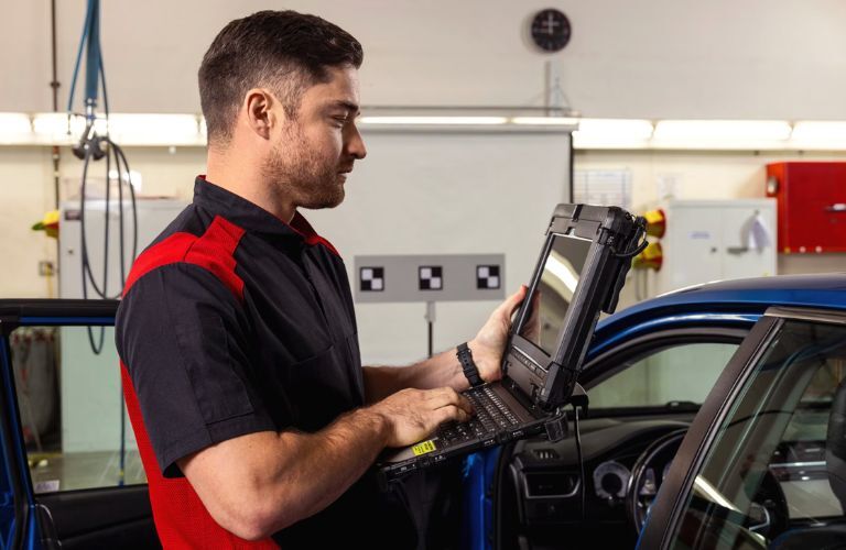 Technician servicing a vehicle while checking details on his screen