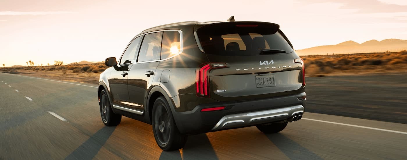 A green 2022 Kia Telluride is driving on an open road.