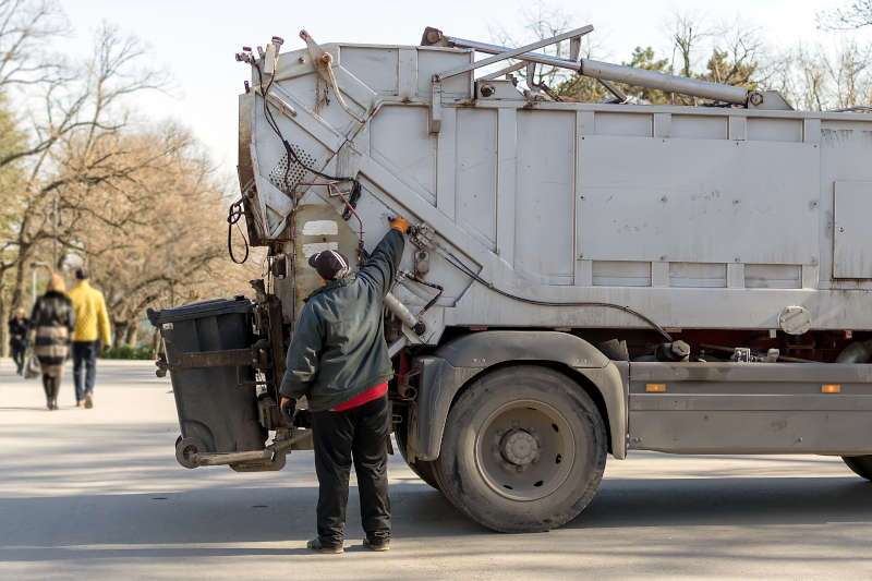 A rear loading garbage truck in action