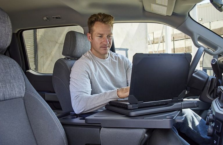 Man sitting inside the 2024 Super Duty F-250 and working on the laptop