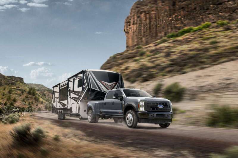 A front 3/4 view of the 2026 Ford F-450 towing a large camper trailer
