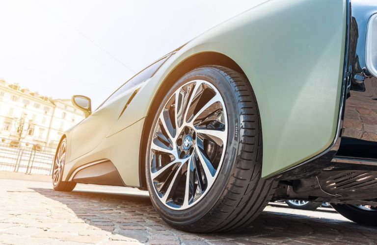 Bottom part of a green color BMW is shown from the angle of a wheel