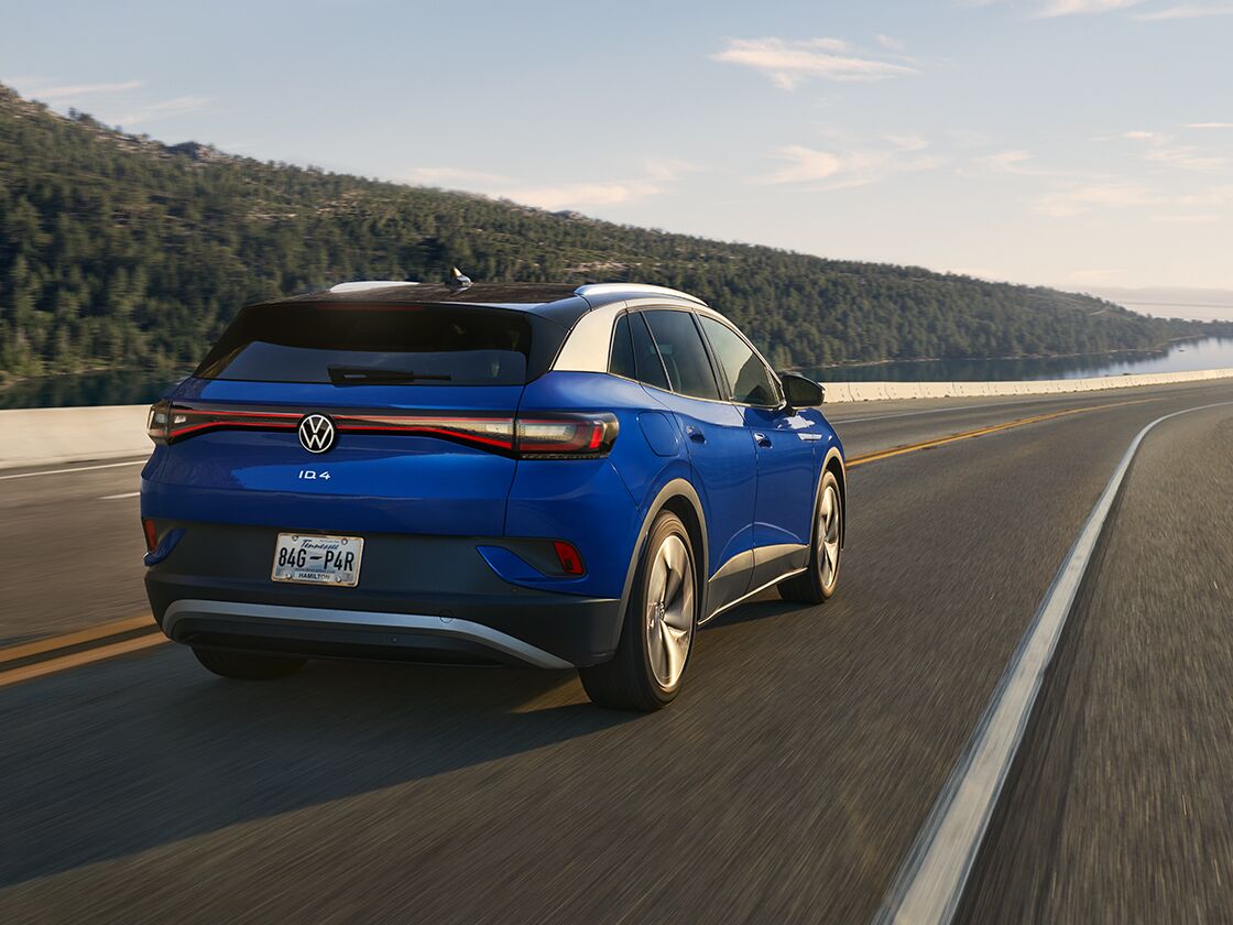 A wide shot of an ID.4 in Dusk Blue Metallic driving along an open highway.