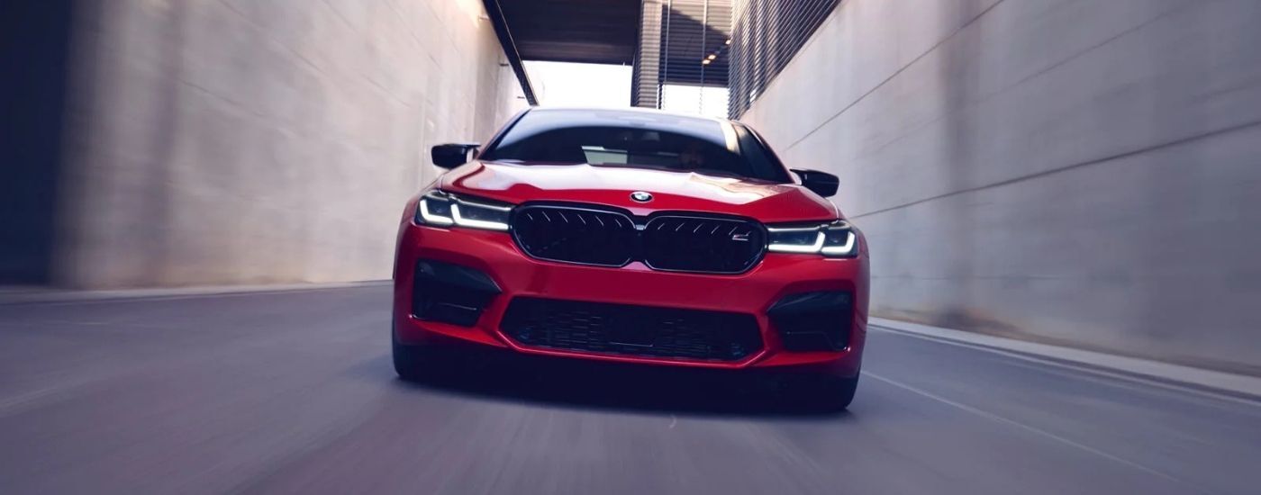 Red 2021 BMW M5 driving through and alleyway