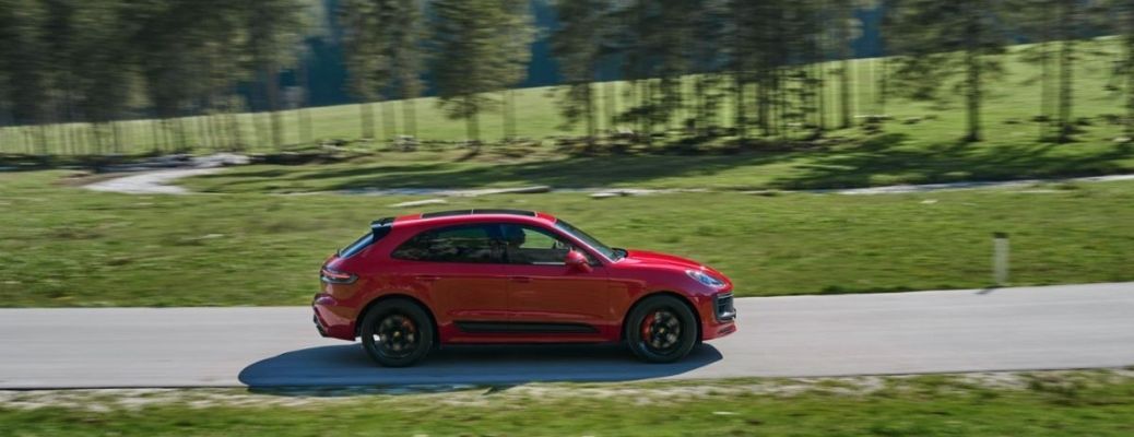 2022 Porsche Macan driving on the road surrounded with lush green grass