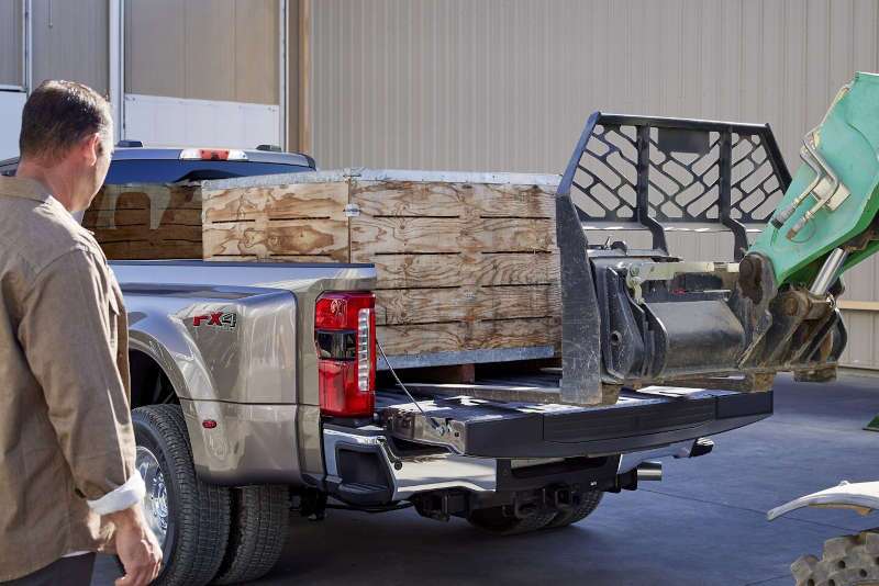 A man loading cargo into the heavy duty truck bed of the 2025 Ford F-250 Super Duty.