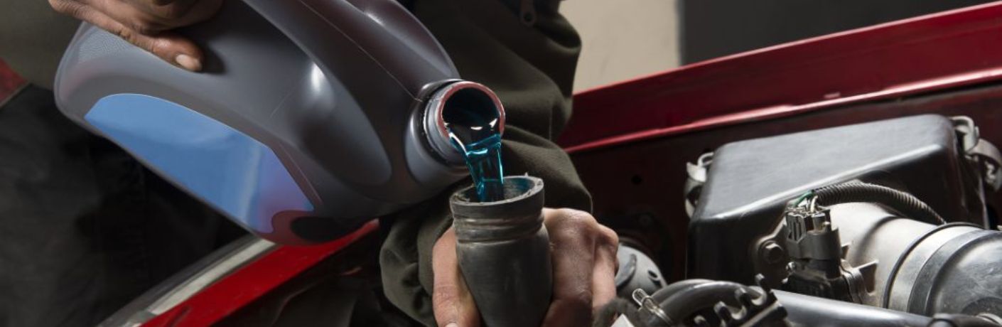 Close up of a mechanic pouring coolant