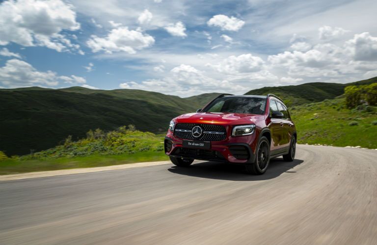 2020 MB GLB exterior front fascia and driver side going fast on highway with green hills in background