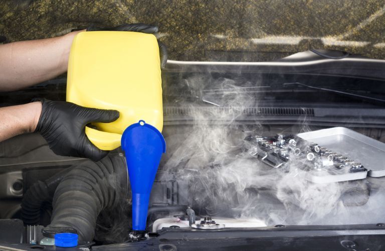 A mechanic pouring coolant