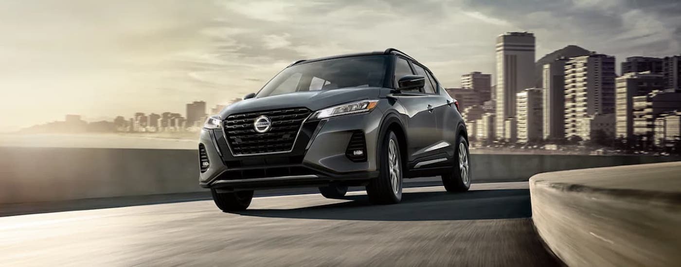 Grey 2021 Nissan Kicks driving down a bridge.