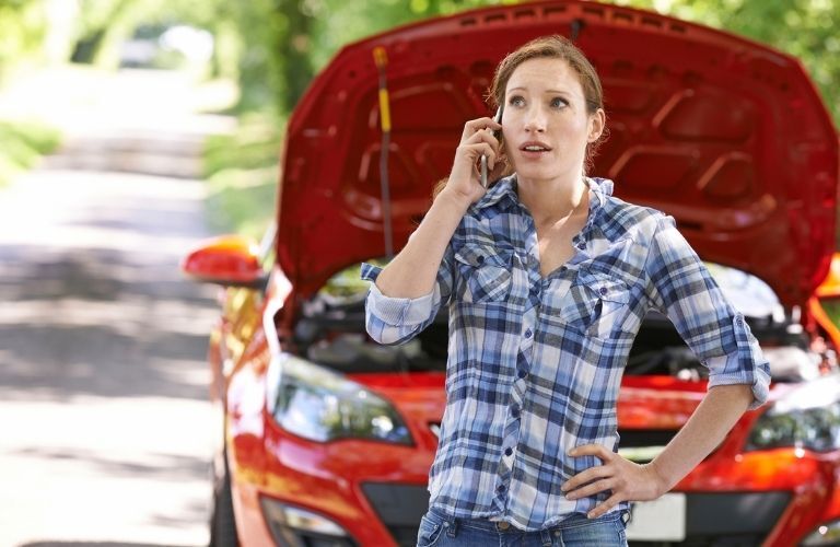 A woman calling with a car in the background