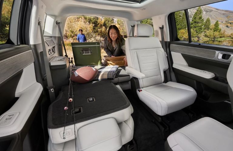 2nd row captain's chairs in the 2025 Hyundai Santa Fe. A woman is adjusting cargo in the SUV.