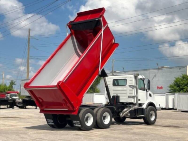 A rear quarter exterior view of a dump truck with its bed elevated