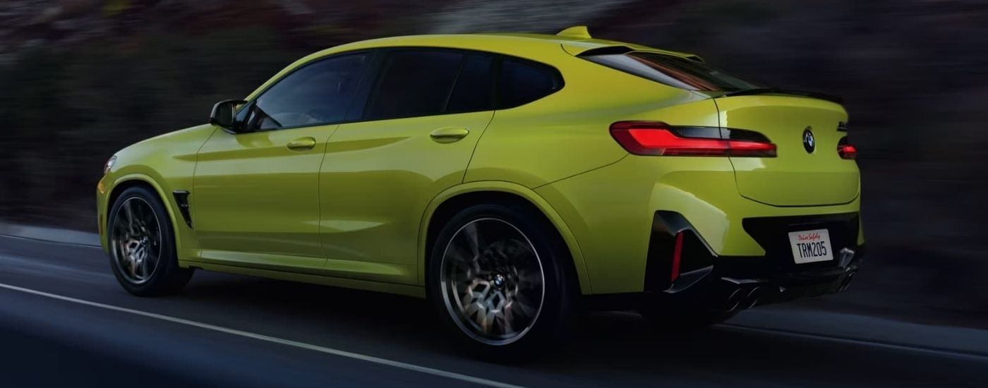 Yellow 2024 BMW X4 M driving on a highway