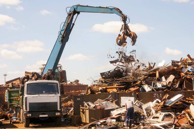 A grapple truck putting construction refuse onto a pile.