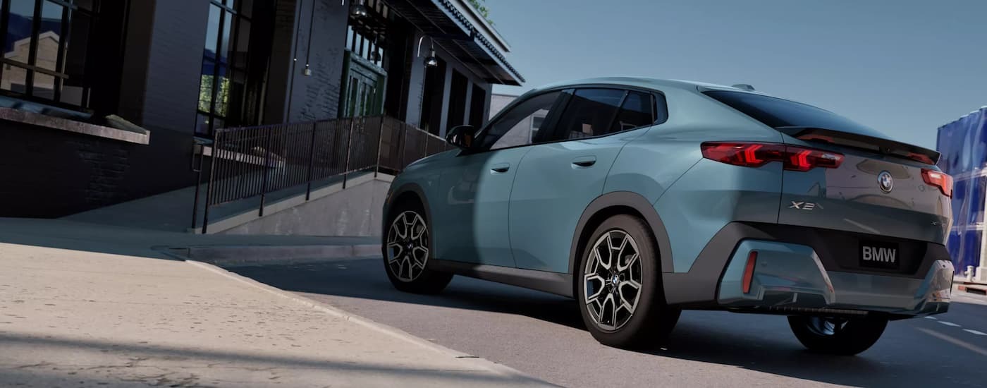 Rear of a blue 2025 BMW X2 parked outside a building.
