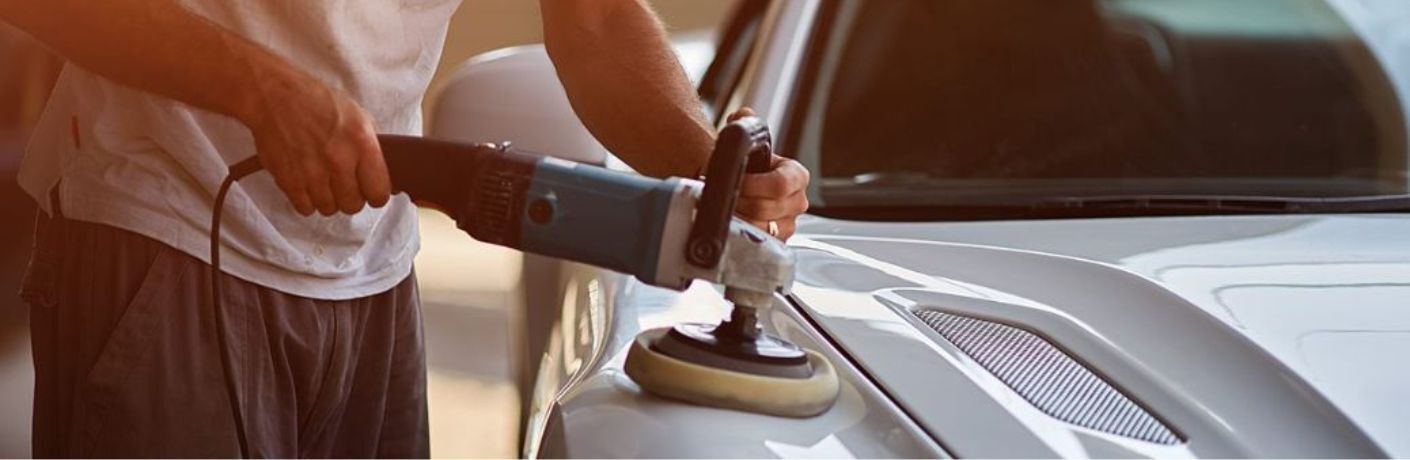 Car Mechanic undertaking detailing with a polishing instrument