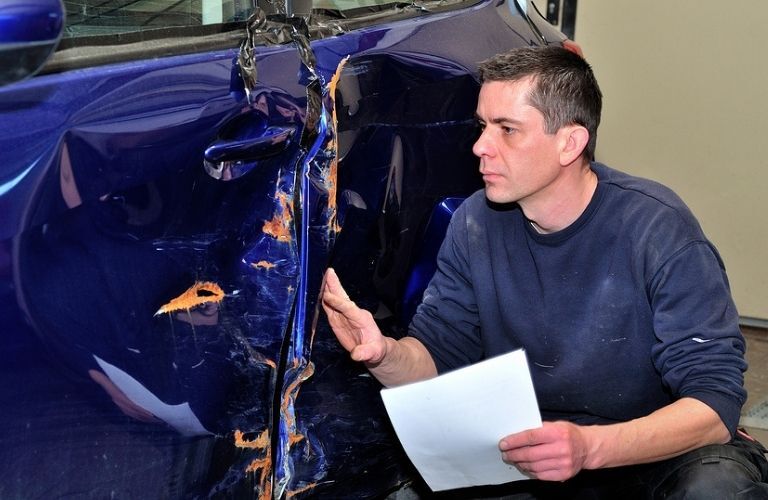 A mechanic inspecting a damaged car
