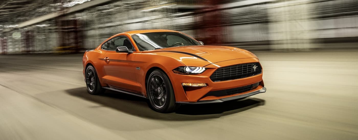 An orange 2021 Ford Mustang is driving through a tunnel after leaving a used car dealership near Union City.