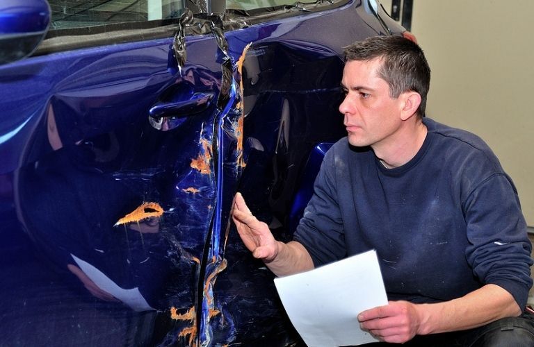 A mechanic inspecting a damaged car