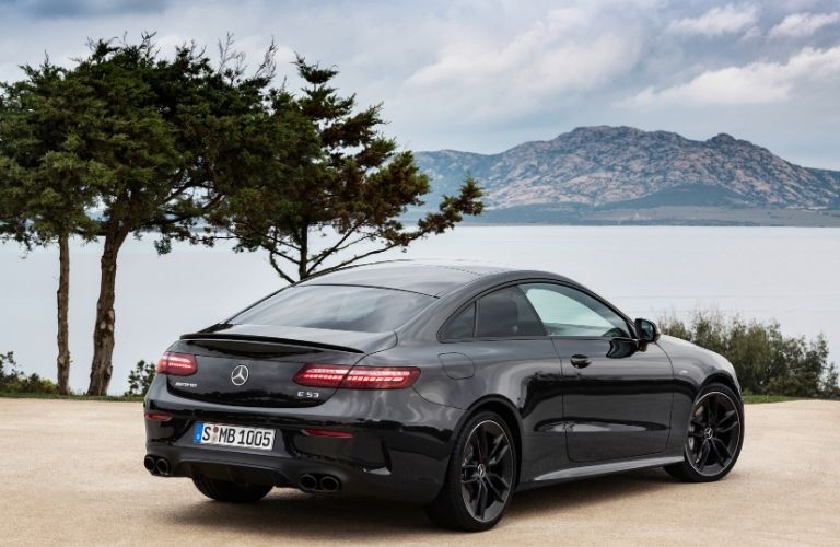 2021 MB E-Class Coupe exterior rear fascia passenger side in front of trees and lake