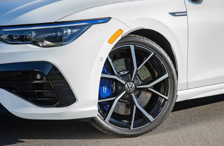Close up of the wheel of a white color 2022 Volkswagen Golf R is shown.
