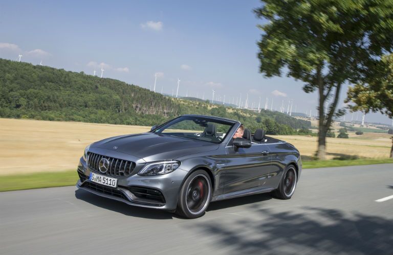 2019 MB C-Class Cabriolet exterior front fascia and driver side going fast on country road with windmills in distance