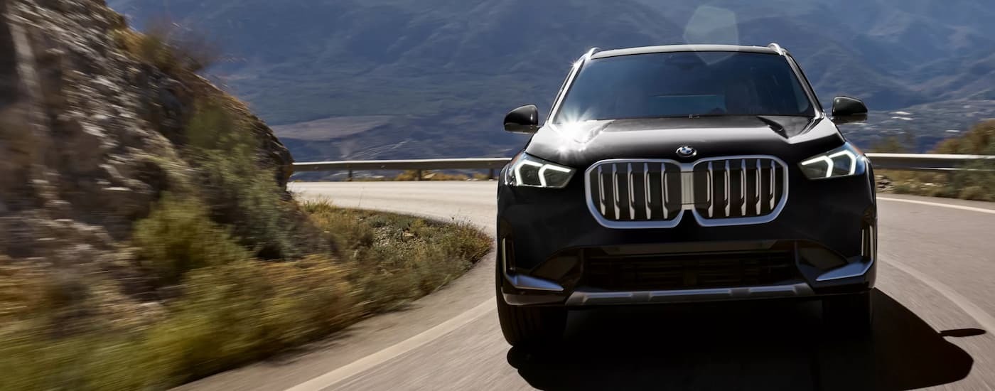 Black 2026 BMW X1 driving around a bend.
