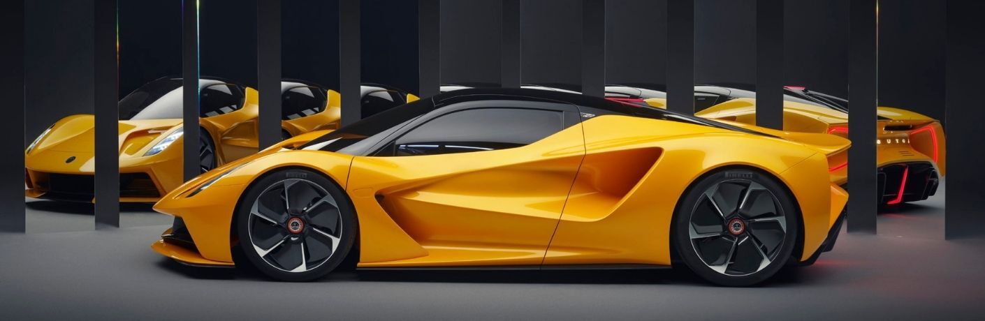 Side view of an orange 2023 Lotus Evija all-electric hypercar parked in a room with mirrors