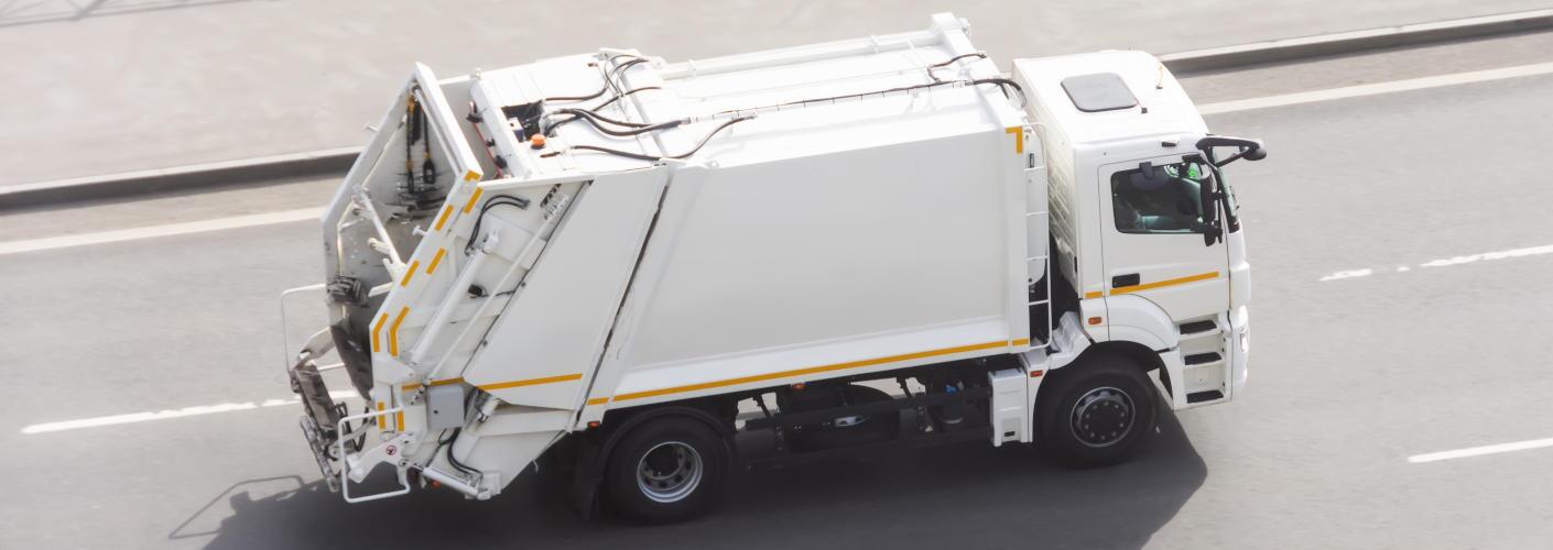 An Autocar garbage truck on the road.