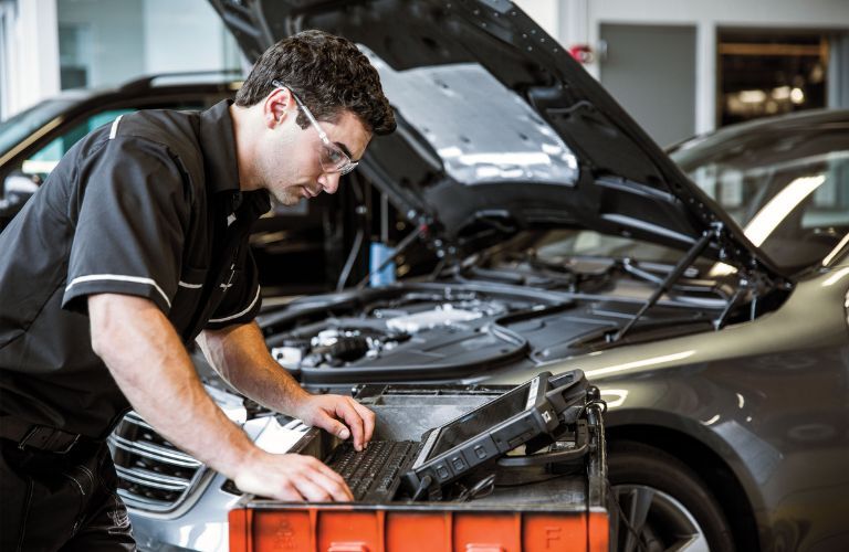 technician looking under the hood of a MB