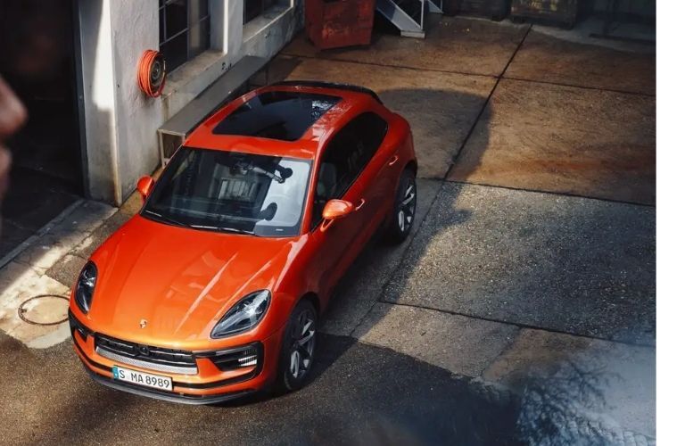 C:\Users\RoRaj\Downloads\Top view of an orange 2022 Porsche Macan in a road
