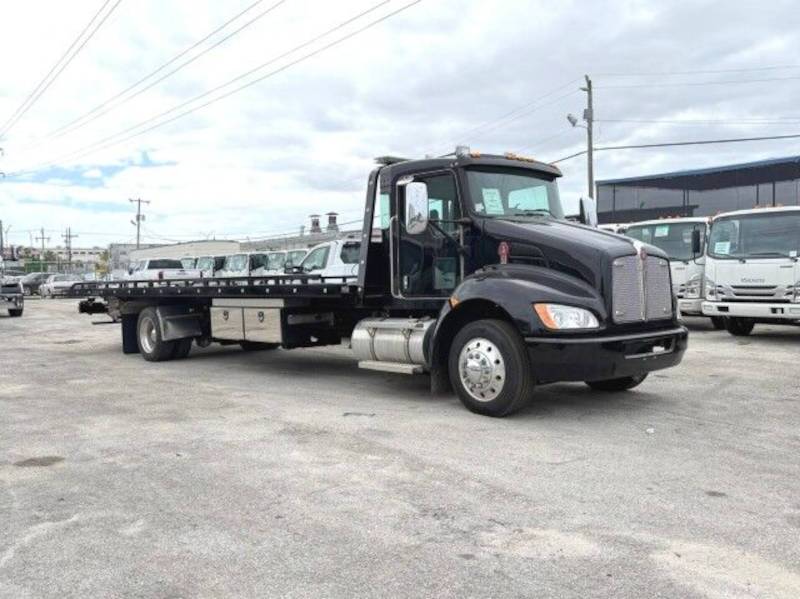 A front quarter exterior view of a Kenworth flatbed truck with equipped with a Paccar diesel engine