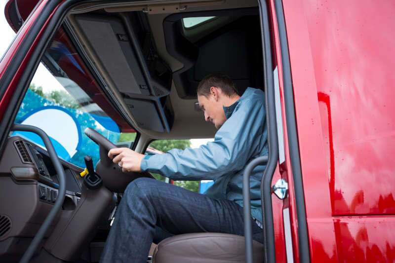 A man in the cab of a tractor trailer truck