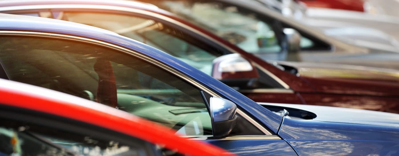 A row of used cars for sale parked at a dealership.